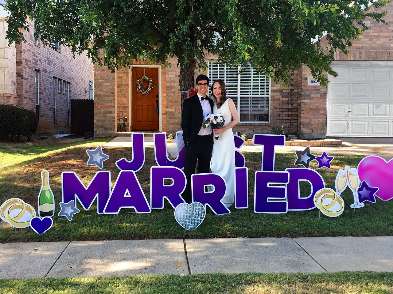 A picture of a bride and groom standing next to a Just Married yard sign greeting