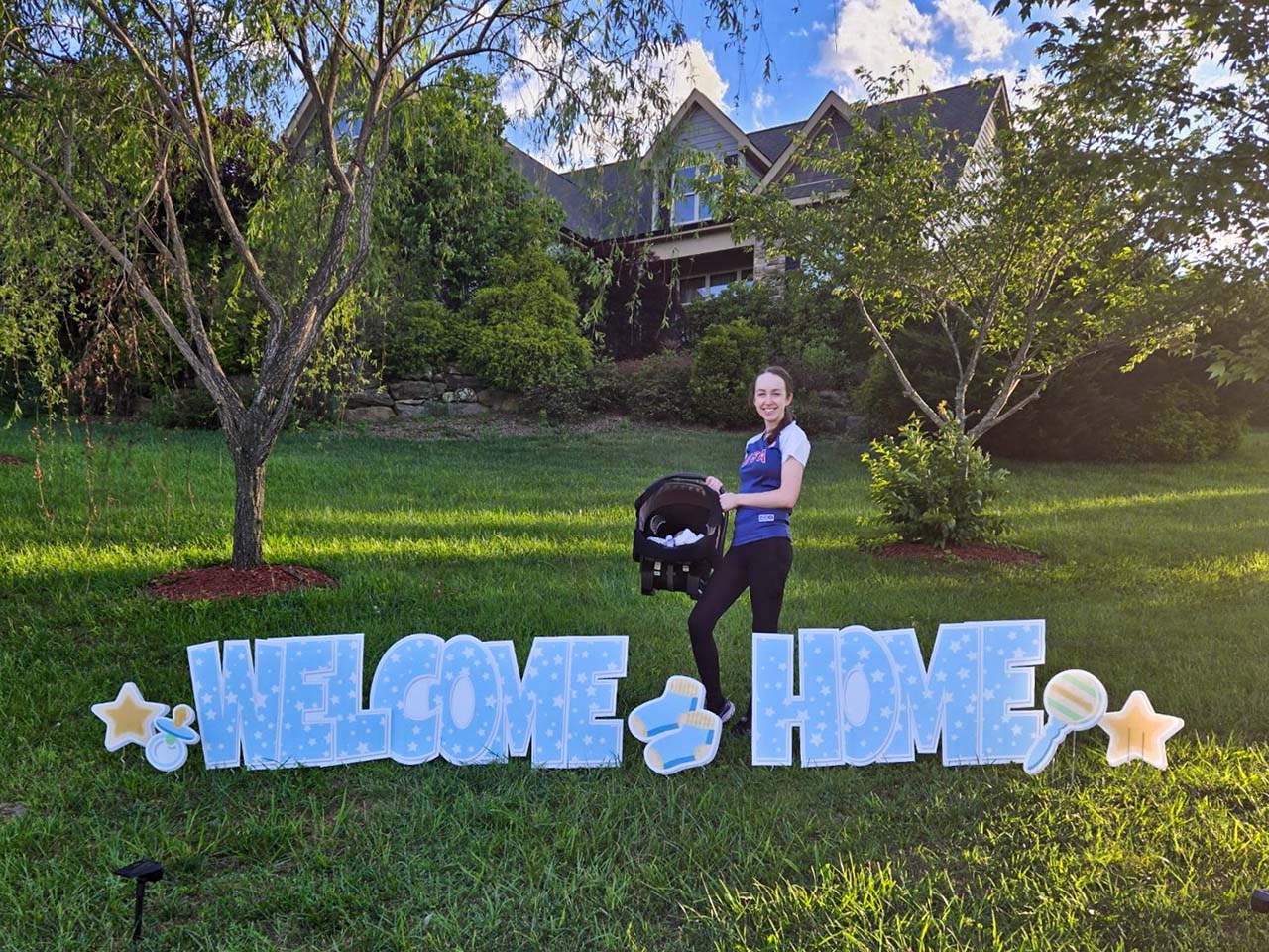 Example of a greeting celebrating a baby boy that reads 'Welcome Home' in baby blue text with decorative signs featuring stars and a pacifier